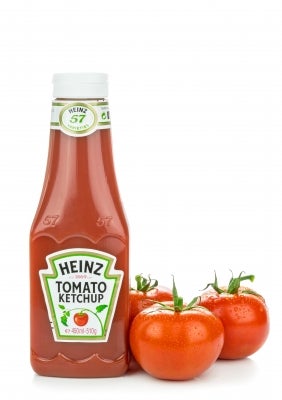 Heinz tomato ketchup bottle with three fresh tomotos on a white background