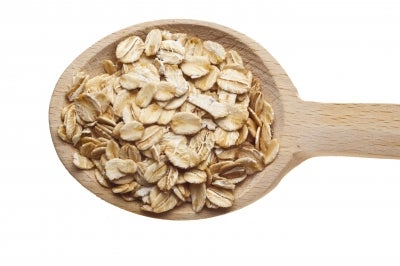 oats on a wooden spoon, white background